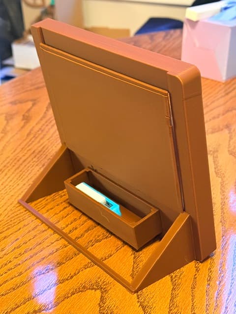 The back of a 3D-printed photo frame stand, showing its hidden storage compartment open